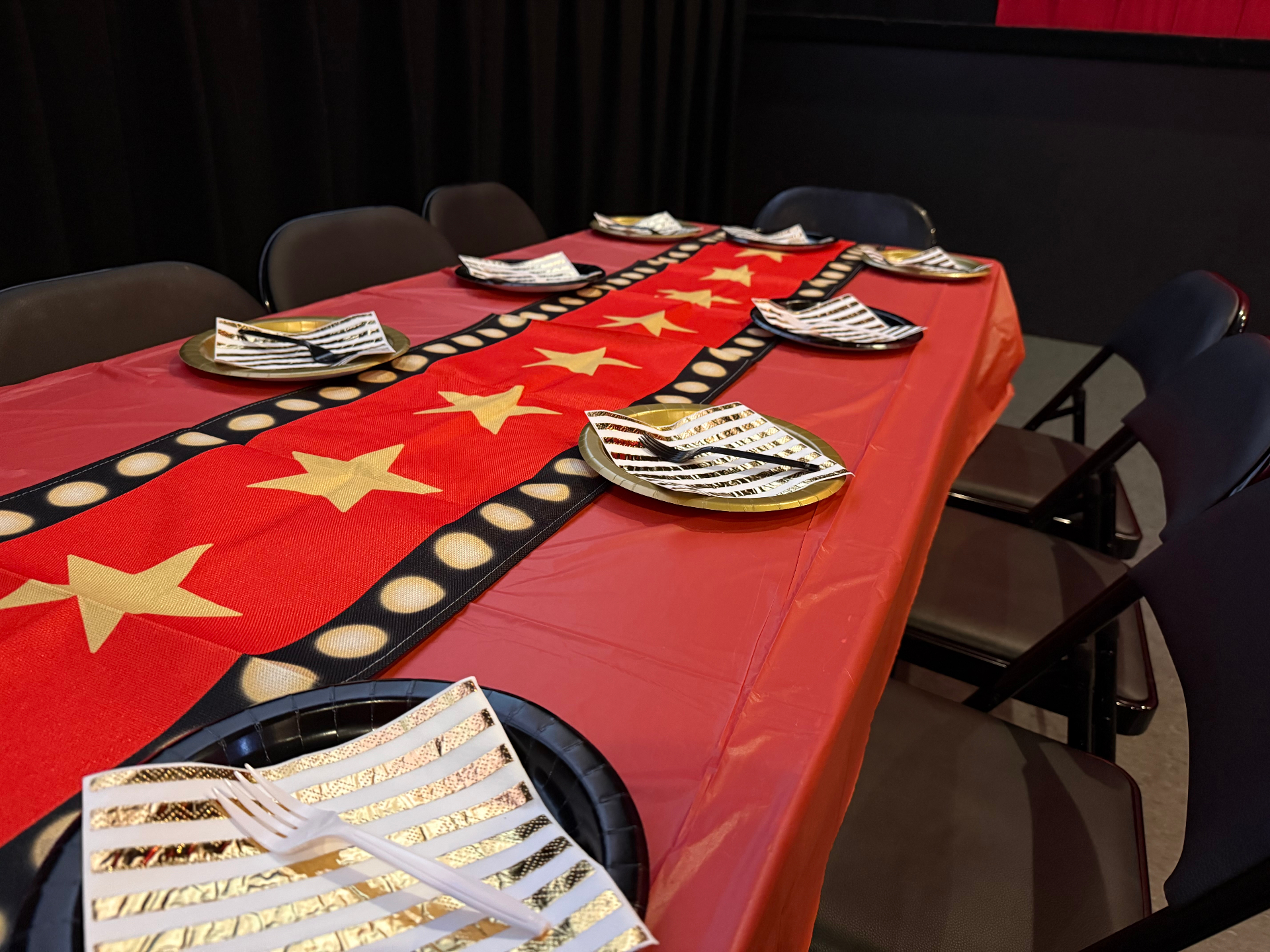 Red-carpet table setup for cake, gifts and guests.